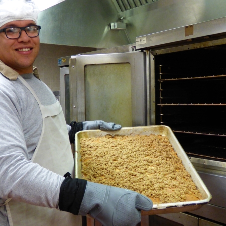 Incarcerated Food Service Worker putting a tray of food in the oven